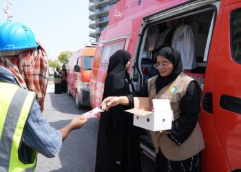 GDRFA officers distributing cold drinking water and refreshments to outdoor workers in Dubai during summer.