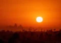 Sun shining brightly over a high-rise city skyline in the Middle East during a summer heatwave