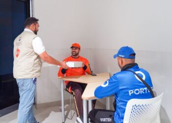 Delivery riders receiving meals at a Dubai metro station rest area during the summer midday break.
