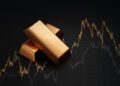 Stack of gold bullion bars and financial market trading screen display